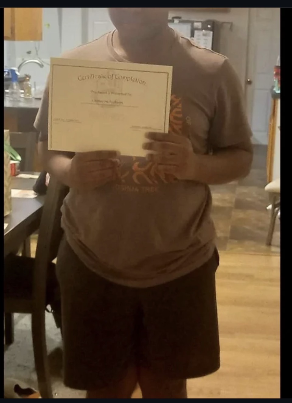 Graduate holding his Certificate of Completion at home