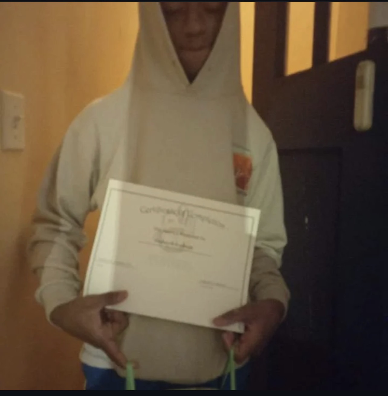 Student in a hoodie displaying his Certificate of Completion
